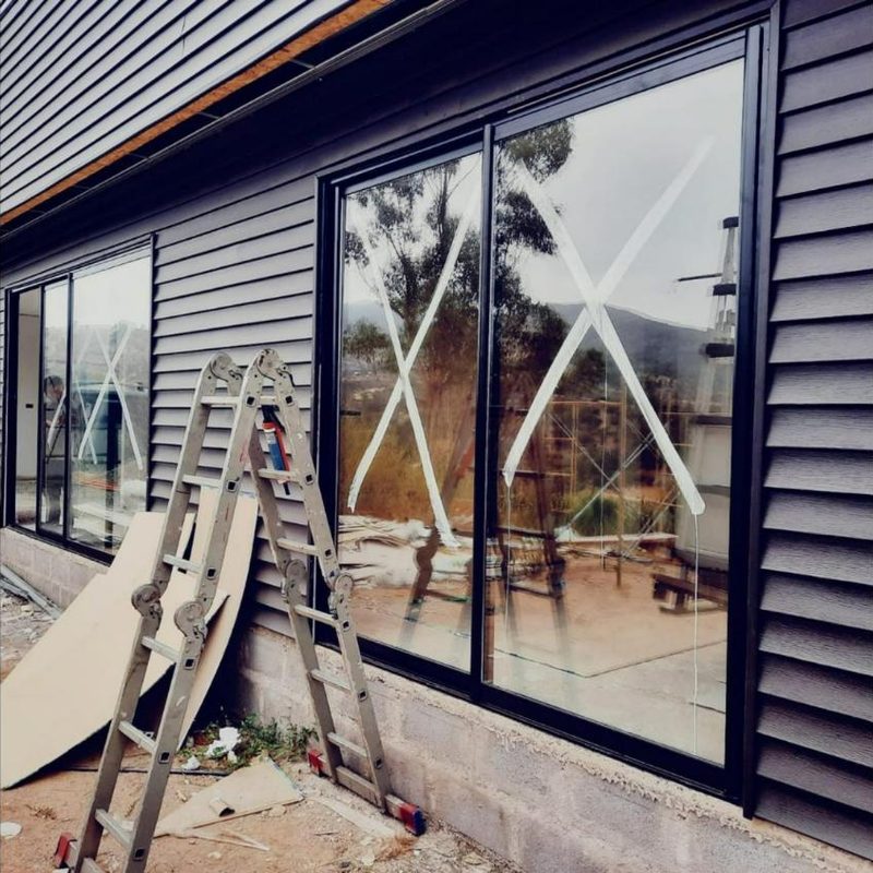 Ventanales negros de PVC instalados en una casa con revestimiento gris